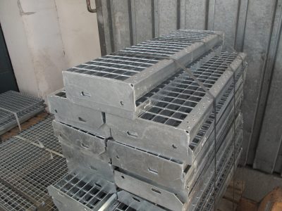 Stacked metal grating panels secured with straps, ready for storage or shipment.